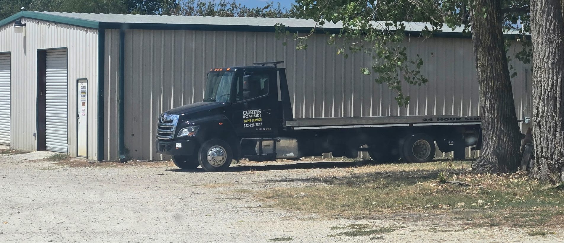 Curtis Roadside empty black flatbed parked at the shop building