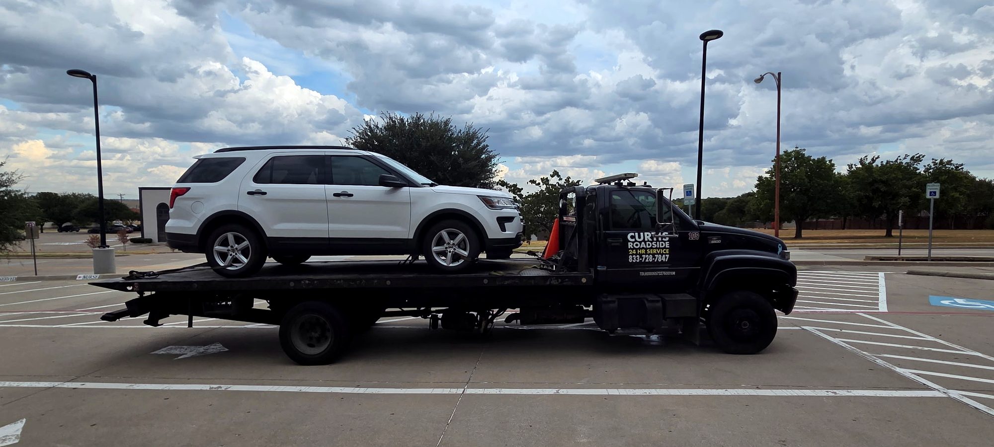 White Ford Explorer loaded on a Curtis Roadside flatbed