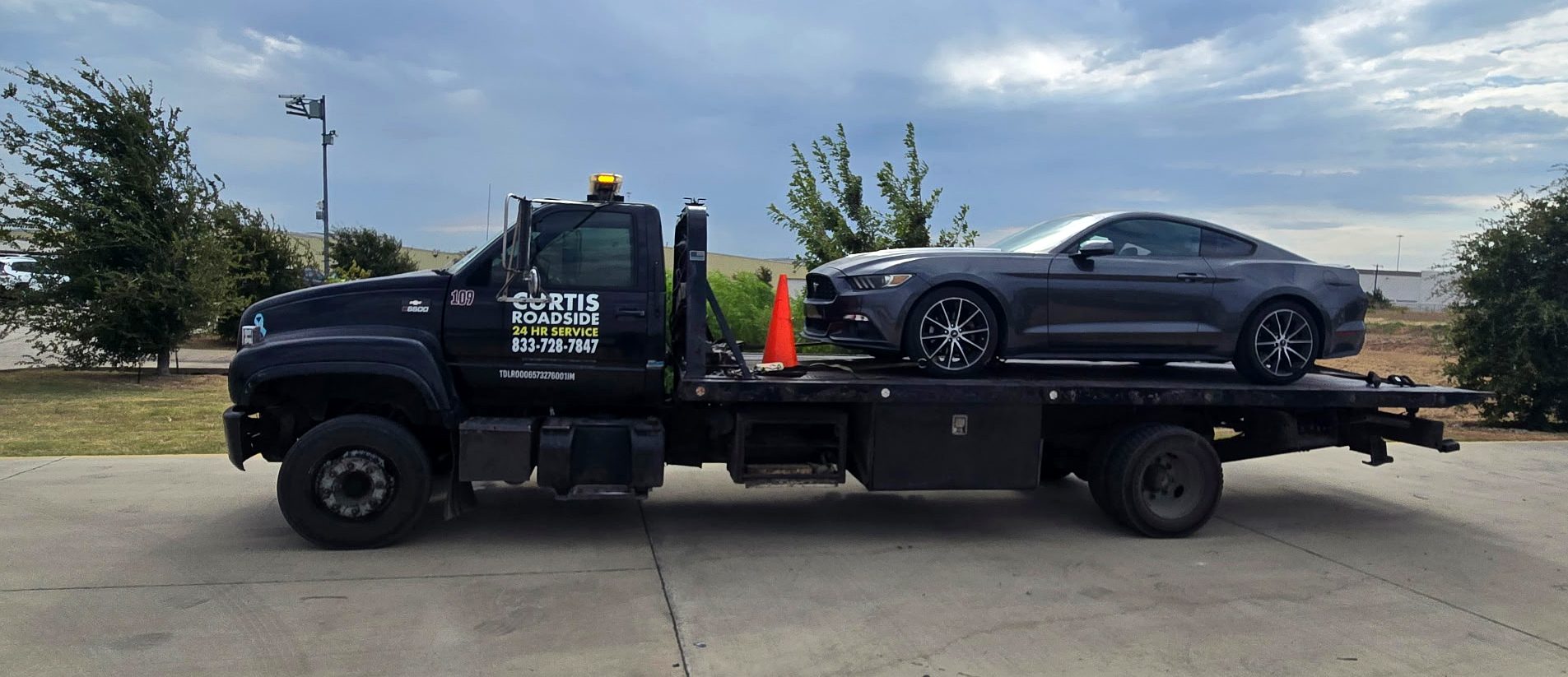 Dark Mustang on a Curtis Roadside flatbed tow truck