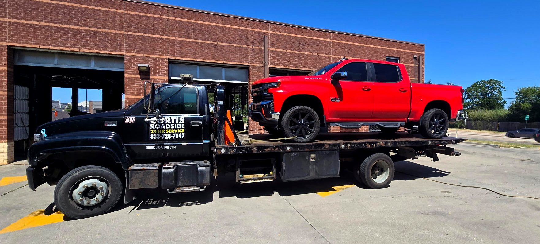 Red Chevrolet Silverado strapped on a Curtis Roadside flatbed
